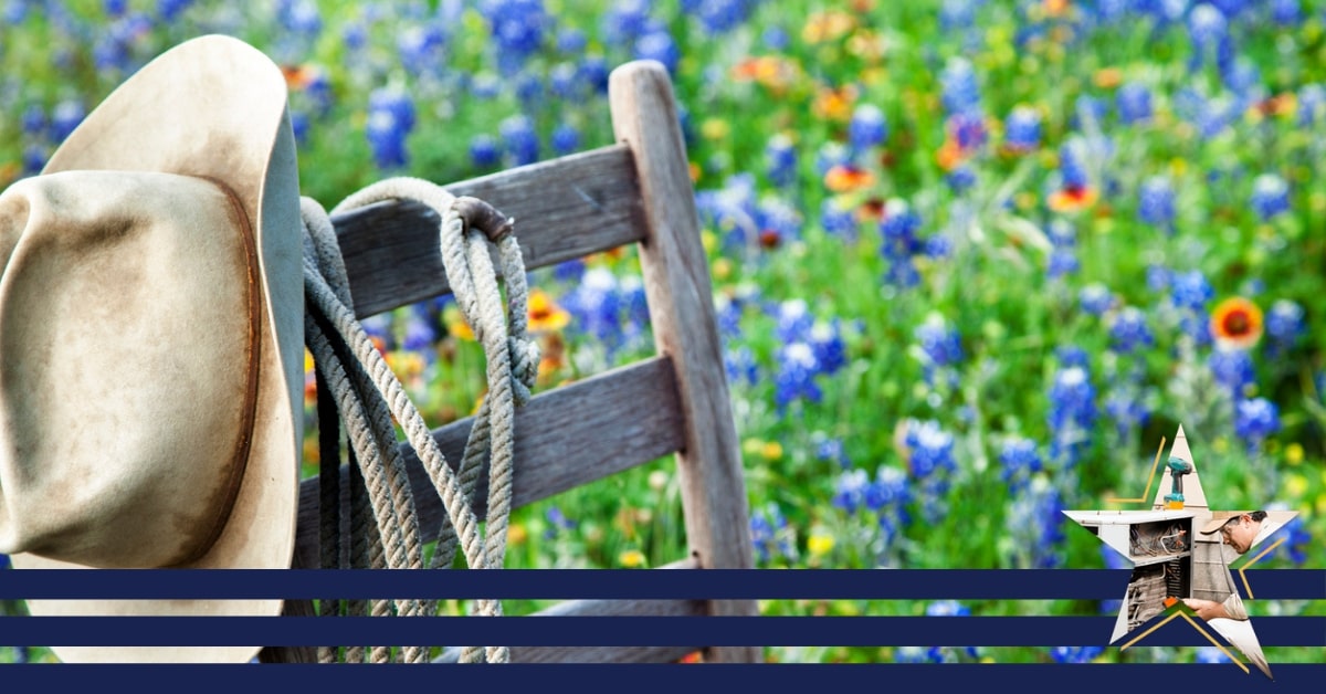 A wooden chair with a hat and rope on the back sitting in a meadow