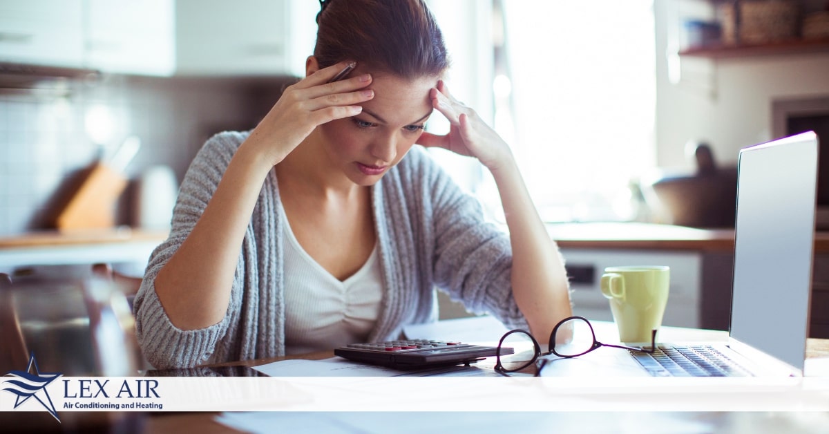 A woman with her hands on her head in front of a computer