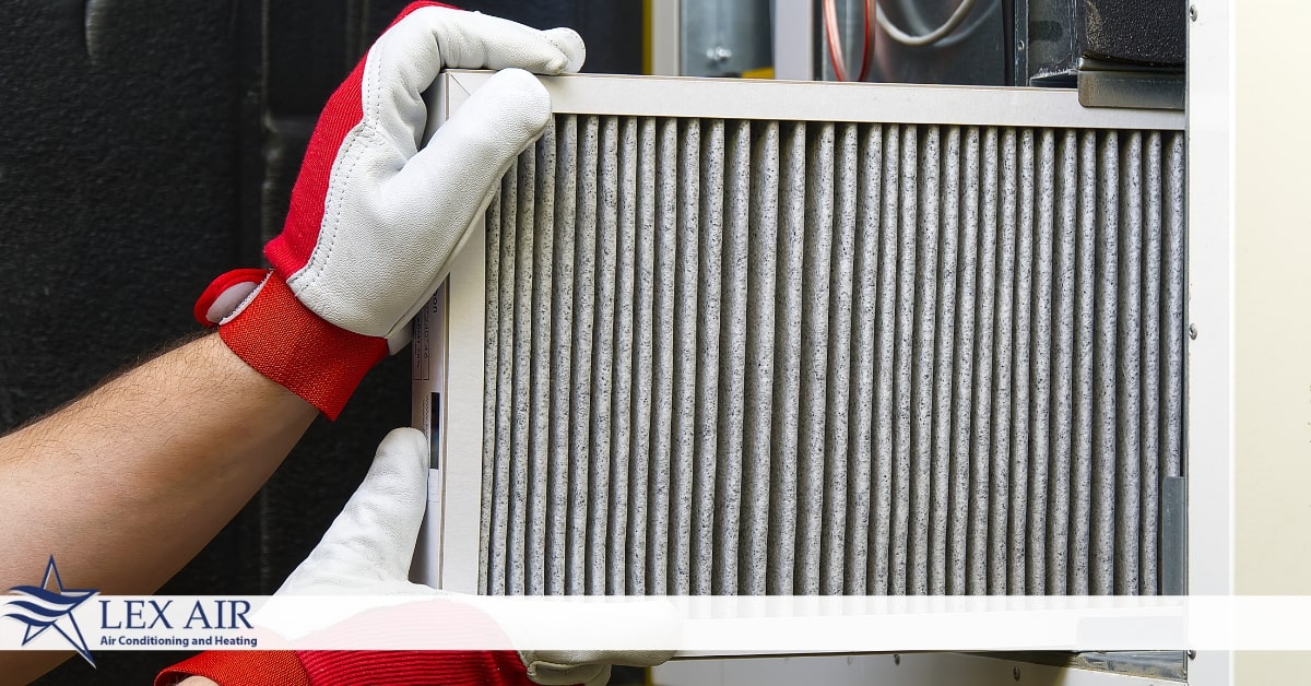 Someone inserting an air filter into an HVAC system