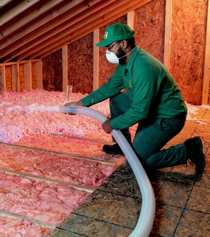 Technician installing blown-in insulation in attic