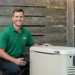 %Imagetitle% | Lex Cooling, Heating Plumbing &Amp; Electrical Man in a green polo shirt kneeling beside a Generac generator, holding a phone, with a wooden fence in the background.